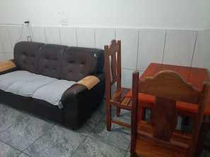 Ein Zimmer mit einem dunkelbraunen Sofa, einem Holzstuhl und einem kleinen Holztisch.