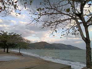 Ein Strand mit Blick auf das Meer und Berge im Hintergrund.