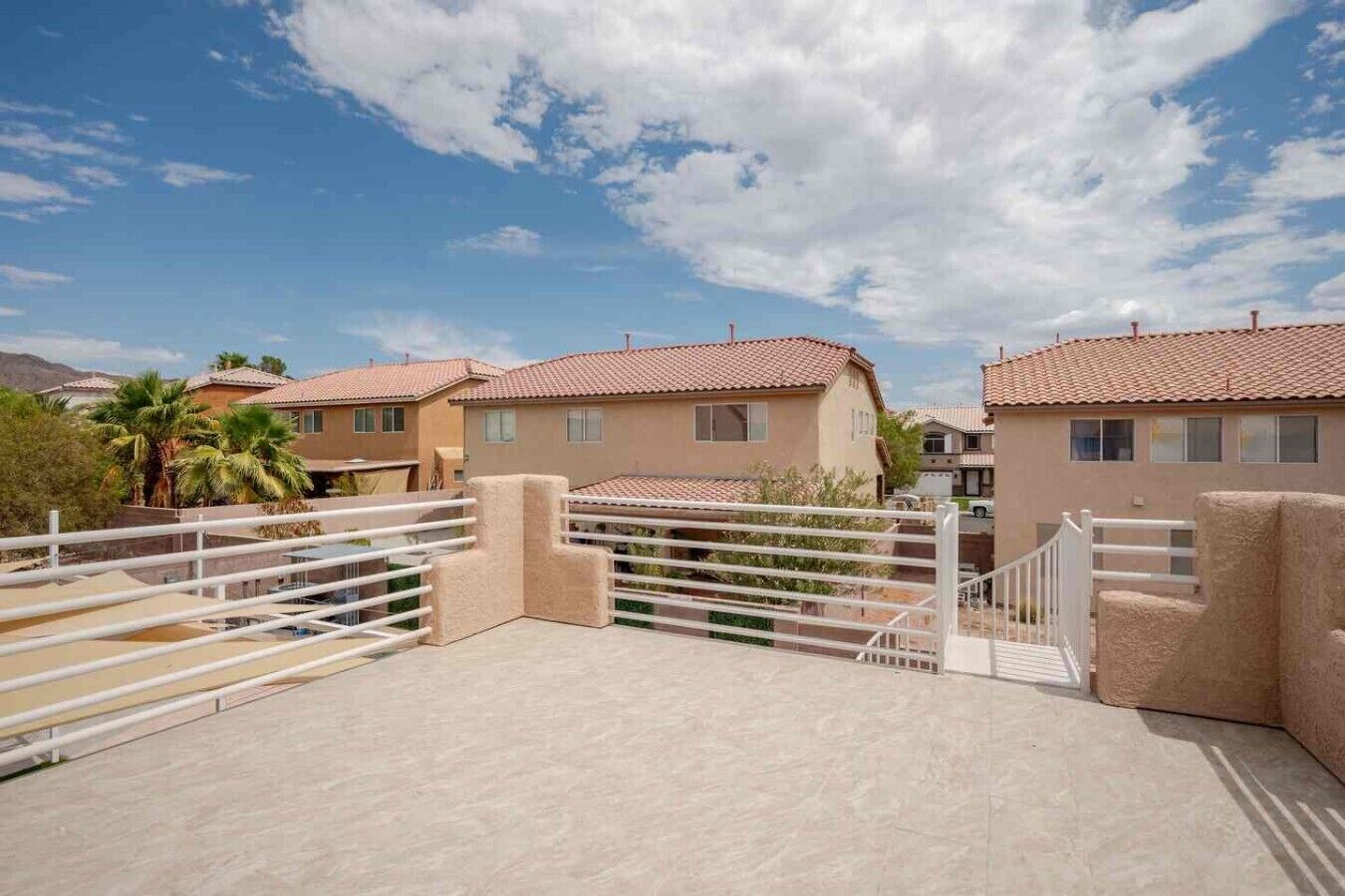 Zona residencial con casas, un acceso con reja y cielo despejado.