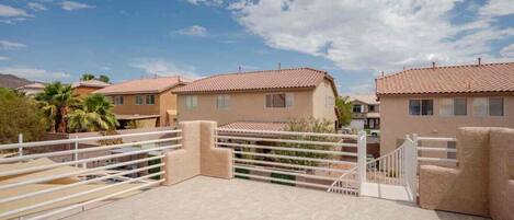 Zona residencial con casas, un acceso con reja y cielo despejado.