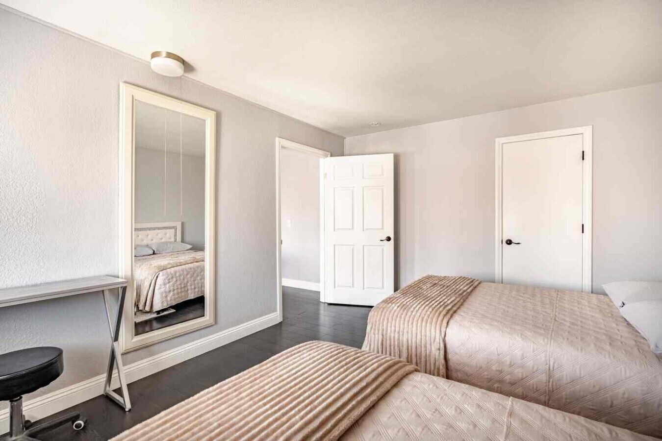 Una habitación de hotel con una cama, un espejo, un escritorio y una silla.