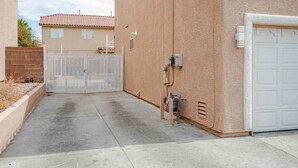 A gated driveway leading to a building with a garage door, a utility box, and a fence. - 5BR Pool House + Billiards · Up to 15 Guests (Las Vegas)