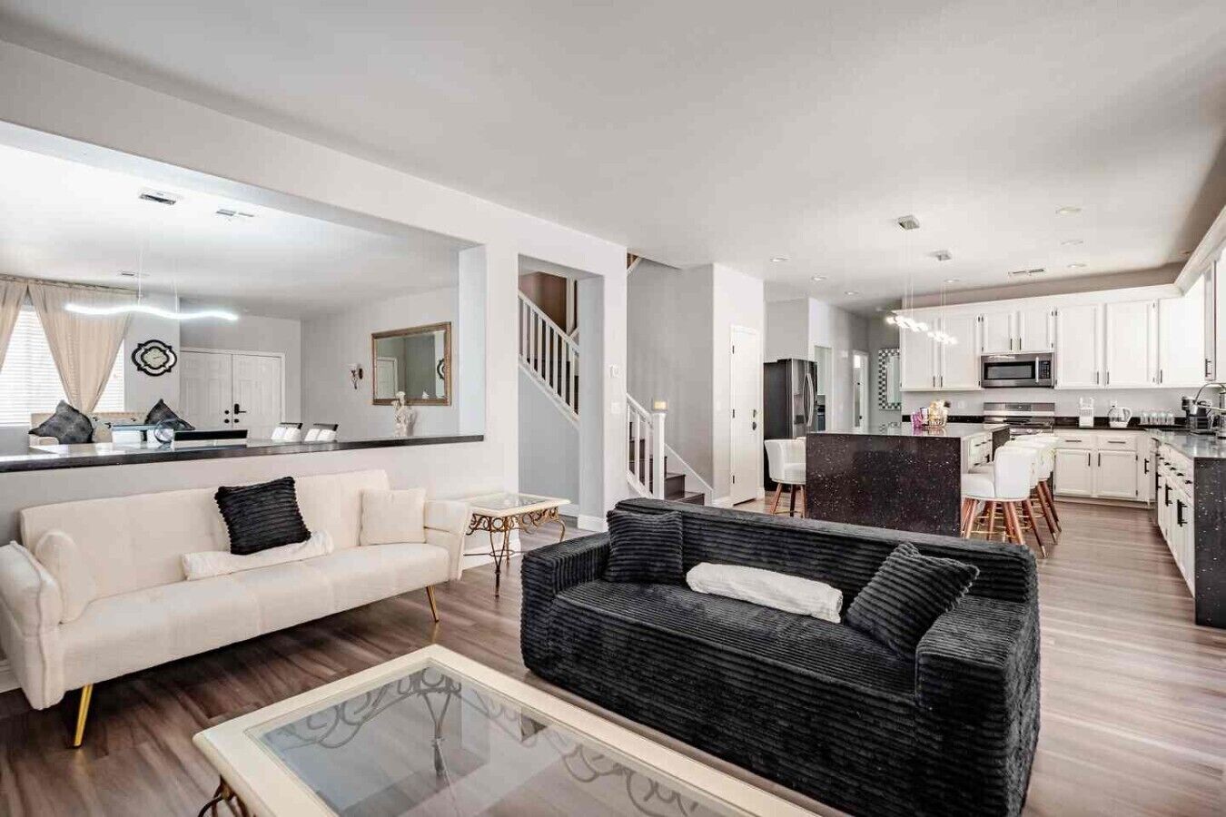 Un salon moderne comprenant un canapé, une table basse et un coin repas avec des chaises.