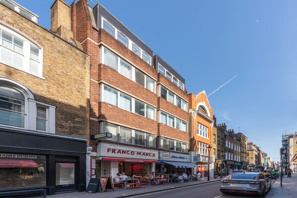 Une vue de rue avec une rangée de bâtiments, dont un restaurant appelé « FRANCO MANCIA », qui dispose d’une terrasse.