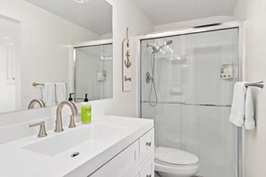 A modern bathroom with a glass-enclosed shower, a white sink with a faucet, and a toilet. - Beautiful Home in the Heart of San Diego! (San Diego)
