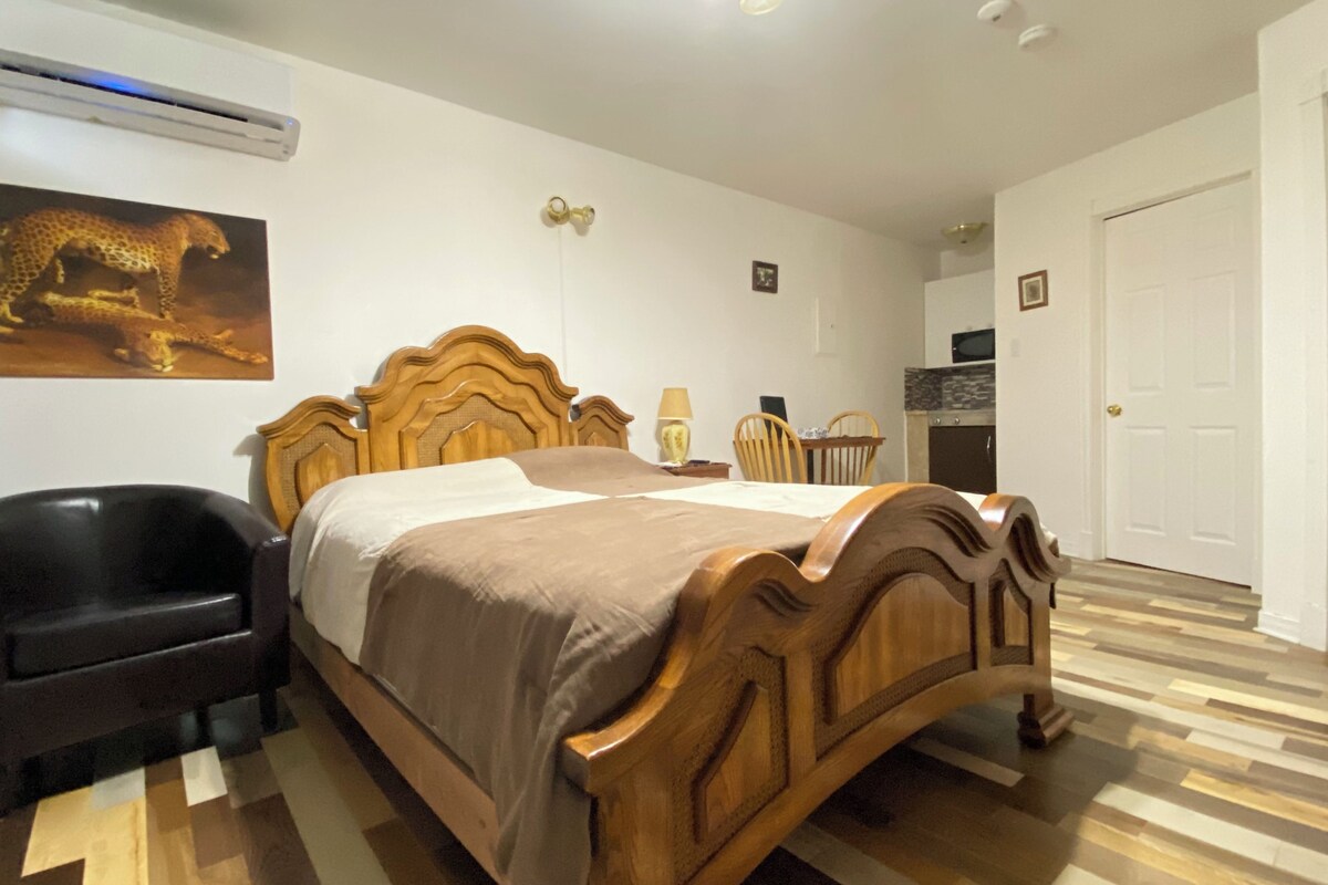 A bedroom with a wooden bed, a chair, a desk, and a door.