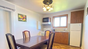 Un coin repas avec une table et des chaises en bois, une cuisine équipée et une fenêtre.