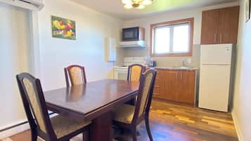 A dining area with a wooden table and chairs, a kitchen with appliances, and a window.