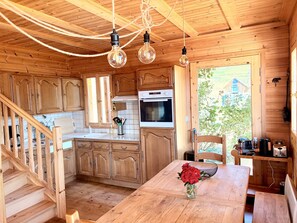A wooden cabin interior with a kitchen, dining area, and a staircase. - Chalet de la Garde - Alpe d'Huez Resort (La Garde)