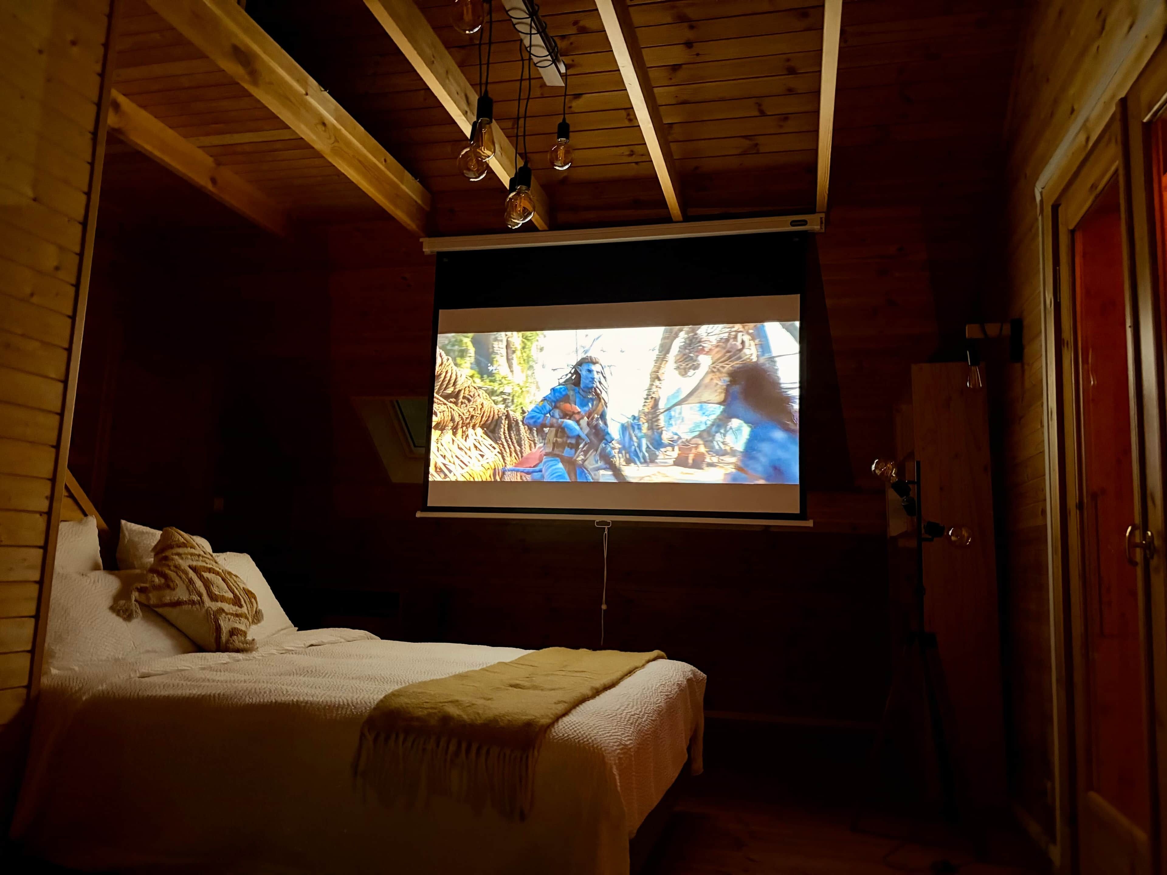 A bedroom with a bed, a television mounted on the wall, and wooden walls.