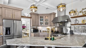 A modern kitchen with a marble island, stainless steel appliances, and a central island sink. - The Pearl Sunset Haven | Luxury Spa Retreat (Seminole)