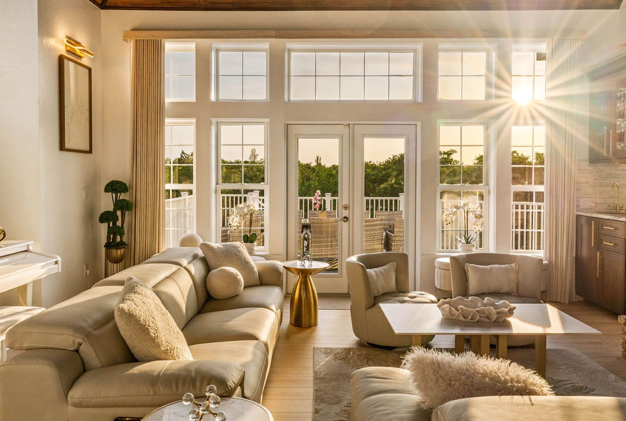 Ein geräumiges Wohnzimmer mit einer großen Couch, einem Couchtisch und Blick ins Freie durch große Fenster.