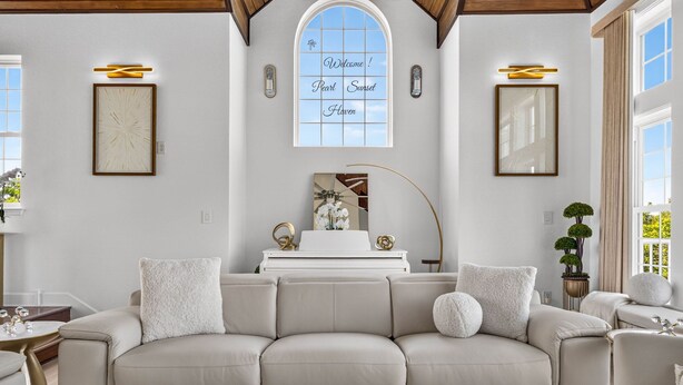 A living room with a beige sectional sofa, a white coffee table, and a decorative mirror. - The Pearl Sunset Haven | Luxury Spa Retreat (Seminole)