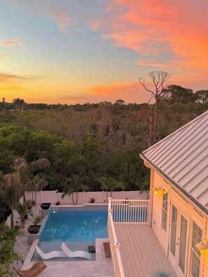 Ein Poolbereich mit Holzterrasse, Liegestuhl und kleinem Whirlpool.