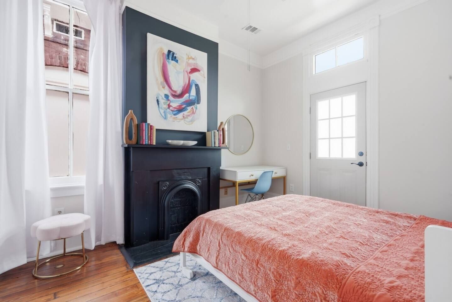 A bedroom with a fireplace, a desk, and a bed.