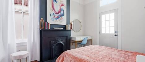 A bedroom with a fireplace, a desk, and a bed.