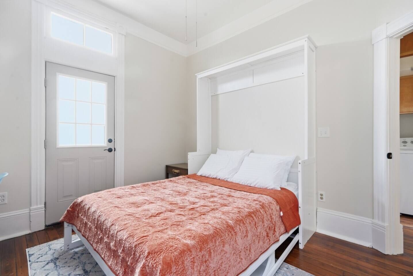 Een slaapkamer met een bed, een raam, een deur en een witte garderobe.