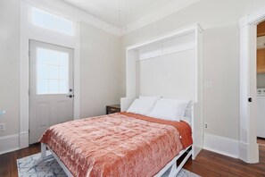 Ein Schlafzimmer mit einem Bett, einem Fenster, einer Tür und einem weißen Kleiderschrank.