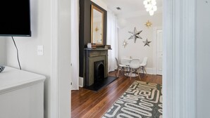 Una sala de estar moderna con chimenea, un comedor con sillas blancas y un televisor montado en la pared.