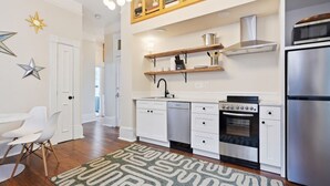 Una cocina moderna con muebles blancos, un refrigerador de acero inoxidable y un horno empotrado.