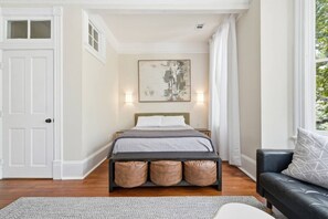 Une chambre à coucher avec un lit, une table de chevet, une fenêtre avec des rideaux et une porte.