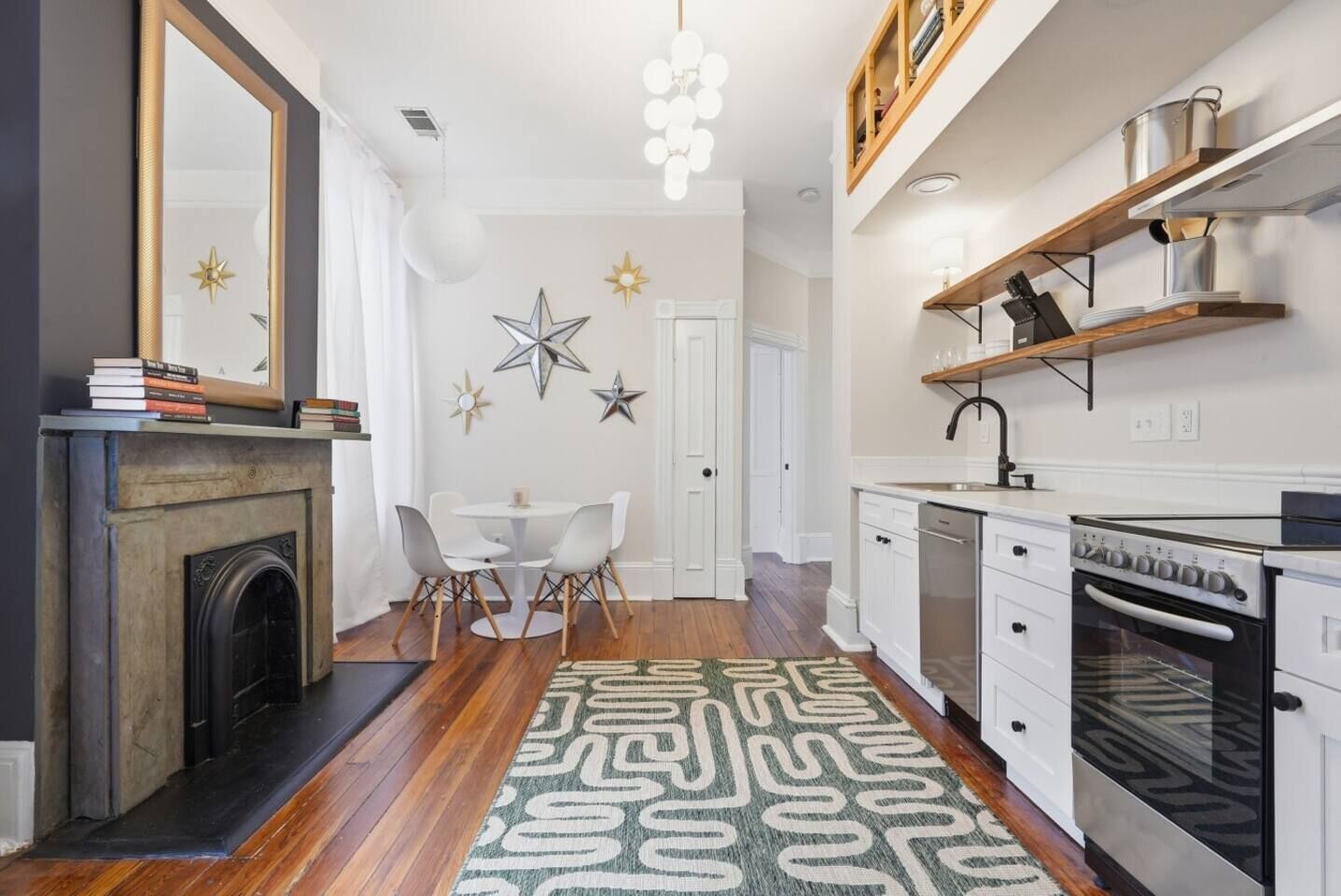 Een moderne keuken met witte kasten, een ingebouwde oven en een eethoek met een ronde tafel en stoelen.