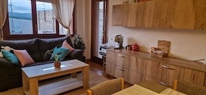 A cozy living area with a sofa, a coffee table, and a view of a building through a window. - La Ampolla by the Sea (L'Ampolla)