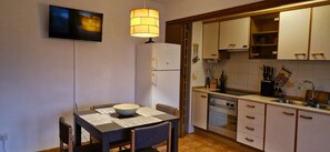 A compact kitchen with a dining table, chairs, a refrigerator, a stove, and a sink. - La Ampolla by the Sea (L'Ampolla)
