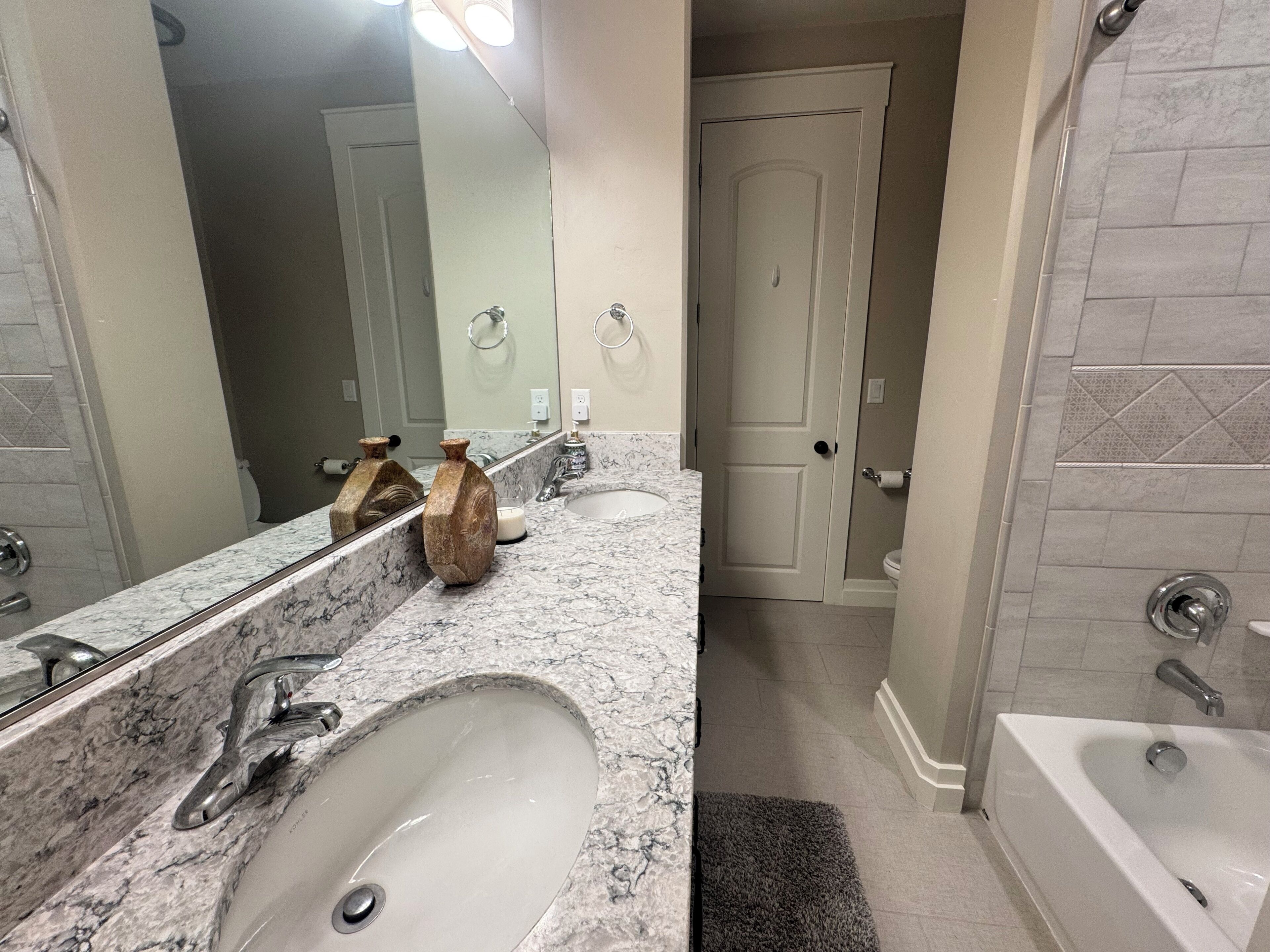 Une salle de bain avec deux éviers, une baignoire et un miroir.