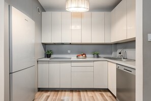 A modern kitchen with white cabinets, a wooden countertop, a built-in dishwasher, and a fruit bowl. - 2-bed Home on Krochmalna (Warsaw)