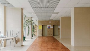 A corridor with a tiled floor, a reception desk, and a plant. - 2-bed Home on Krochmalna (Warsaw)