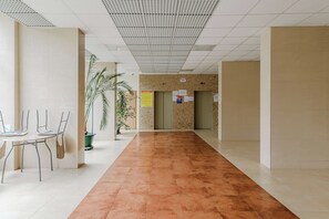 A corridor with a tiled floor, a reception desk, and a plant. - 2-bed Home on Krochmalna (Warsaw)