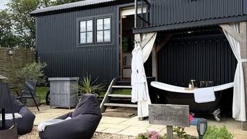 A black metal building with a chimney, a wooden staircase, and a sign reading 'The Black Swan.'