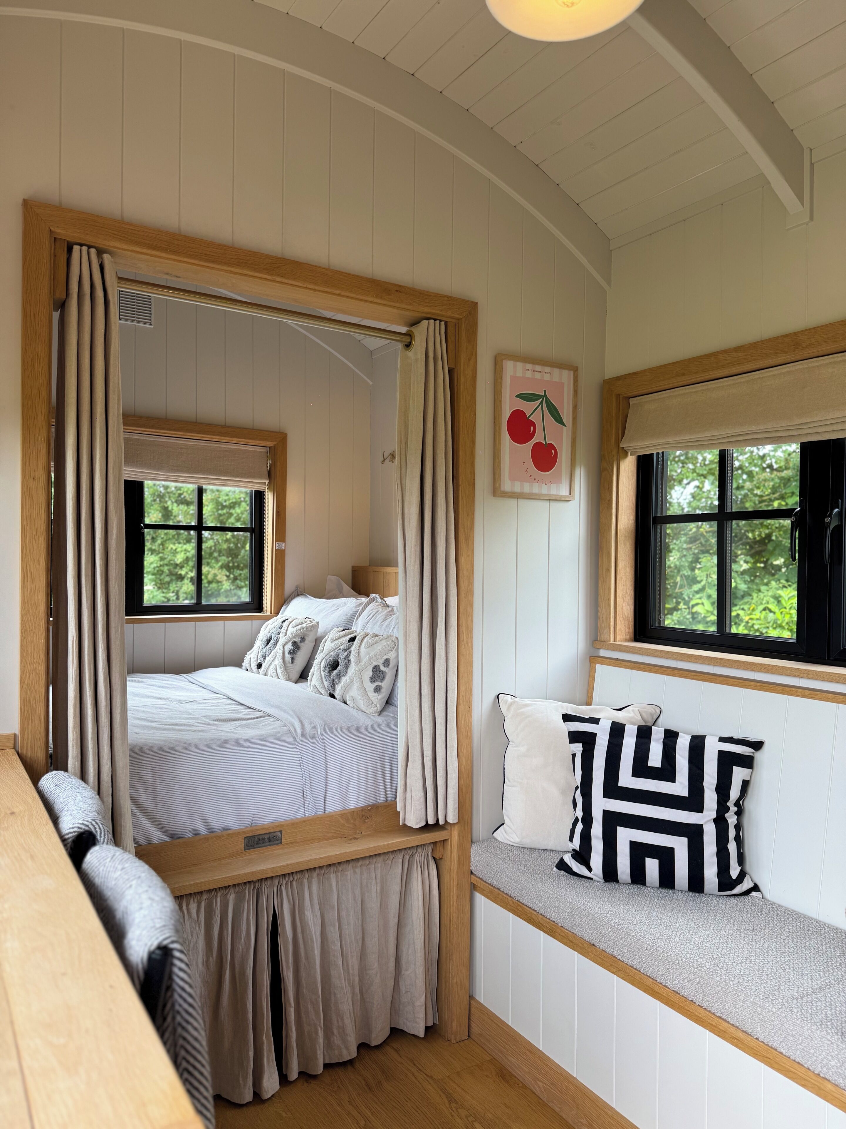 A bedroom with a bed, bench, windows, and a wall-mounted picture.