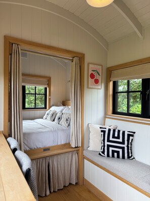 Ein Schlafzimmer mit einem Bett, einer Bank, Fenstern und einem an der Wand hängenden Bild.
