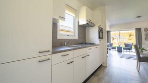 A modern kitchen with white cabinets, a built-in oven, and a window above the sink. - Dog Friendly Chalet Kaatsheuvel (Kaatsheuvel)