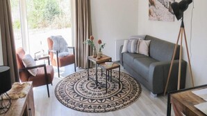A living room with a sofa, a chair, a coffee table, and a floor lamp. - Dog Friendly Chalet Kaatsheuvel (Kaatsheuvel)