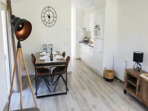 Una cocina moderna con armarios blancos y un comedor con mesa y sillas de madera.