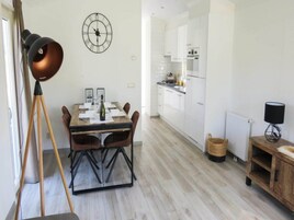 Una cocina moderna con armarios blancos y un comedor con mesa y sillas de madera.