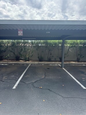 Ein Parkplatz mit überdachtem Bereich, markierten Stellplätzen und einer begrünten Wand.