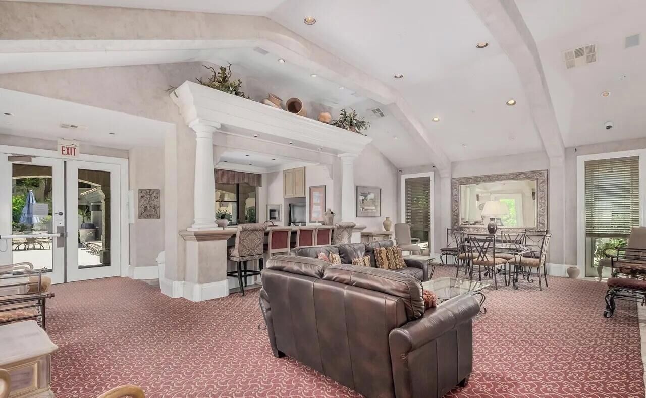 A spacious hotel lobby with a leather sofa, a dining area, and an exit sign.