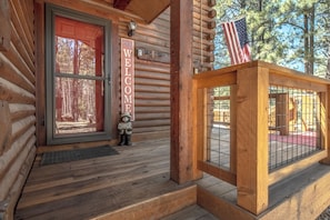 Eine Holzhütte mit einem Willkommensschild, einer Bär-Dekoration und einer amerikanischen Flagge.