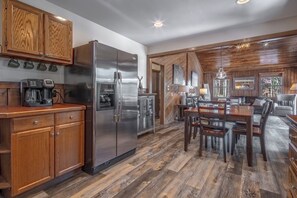 Een moderne keuken met houten kasten, een roestvrijstalen koelkast en een eethoek met een houten tafel en stoelen.