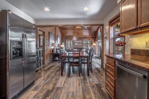 A modern kitchen with a central island, stainless steel appliances, and a wooden floor. - Mountain Cabin Perched Just Above AF Golf Course. Hot Tub. Deck. Family Fun! (Angel Fire)