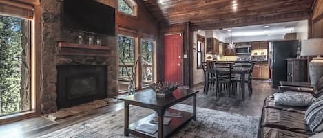 Una sala de estar amplia con chimenea de piedra, un comedor con mesa y sillas de madera, y una cocina con electrodomésticos modernos.