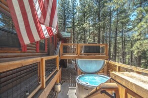 A wooden deck with a hot tub, a wooden fence, and a view of a forest. - Mountain Cabin Perched Just Above AF Golf Course. Hot Tub. Deck. Family Fun! (Angel Fire)