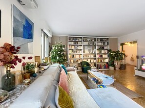 Ein Wohnzimmer mit einer Couch, einem Weihnachtsbaum, einem Bücherregal und einem Couchtisch.