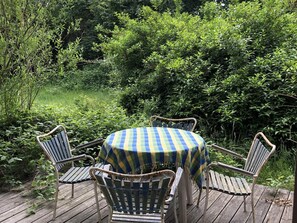 A wooden deck with a round table and four chairs, surrounded by dense greenery. - 4 Star Holiday Home in Vejby (Vejby)