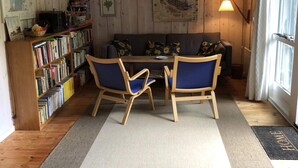 A cozy room with a wooden floor, a sofa, two chairs, a bookshelf, and a lamp. - 4 Star Holiday Home in Vejby (Vejby)