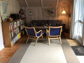 A cozy room with a wooden floor, a sofa, two chairs, a bookshelf, and a lamp. - 4 Star Holiday Home in Vejby (Vejby)